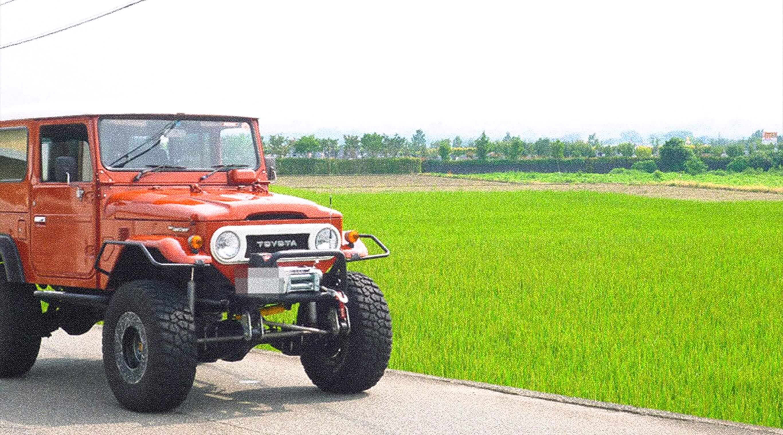 道沿いに停車する赤色の四輪駆動車